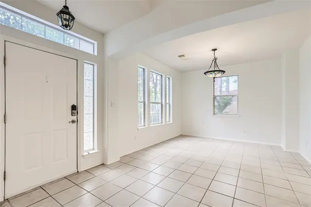 a view of an empty room with window and chandelier fan