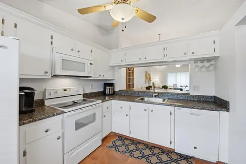 a kitchen with granite countertop white cabinets and white appliances