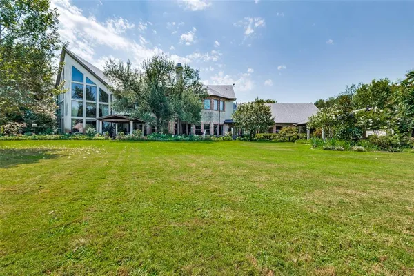 an aerial view of residential house with outdoor space and trees all around