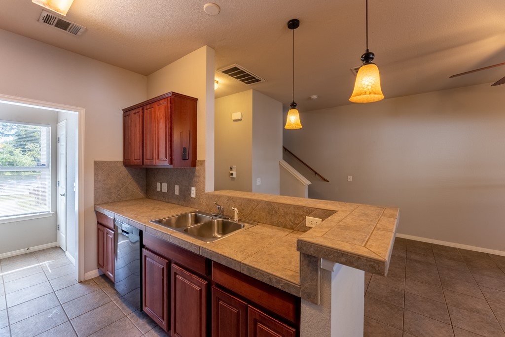 3000 Govalle Avenue, Unit B Austin, TX 78702 - Photo 10 of 26 Kitchen featuring light tile patterned flooring, decorative light fixtures, a breakfast bar area, decorative backsplash, and dishwashing machine