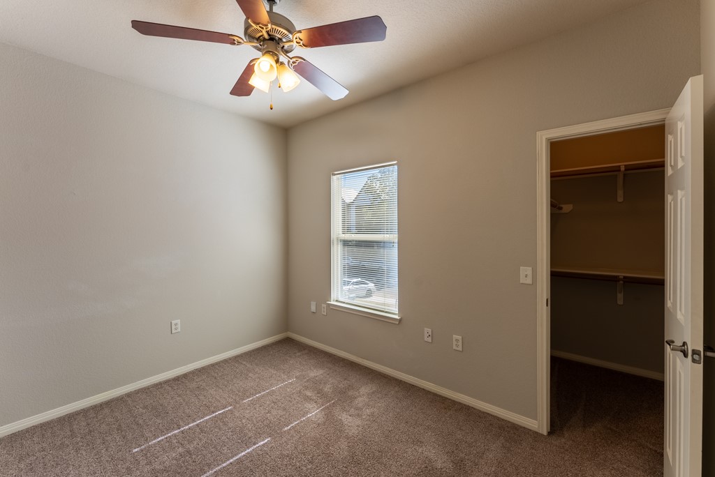 3000 Govalle Avenue, Unit B Austin, TX 78702 - Photo 18 of 26 Unfurnished bedroom with carpet floors, a walk in closet, and a ceiling fan