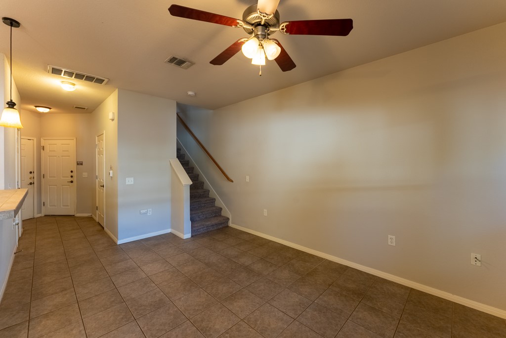 3000 Govalle Avenue, Unit B Austin, TX 78702 - Photo 7 of 26 Empty room featuring stairway, a ceiling fan, and dark tile patterned flooring