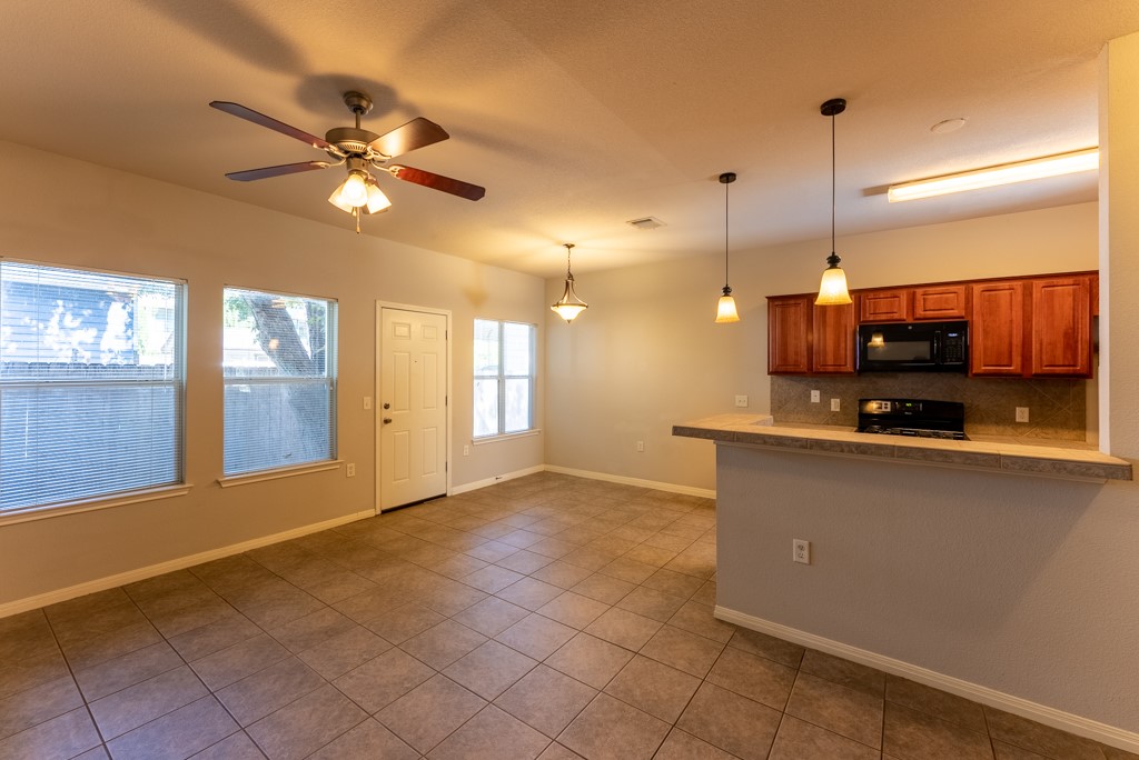 3000 Govalle Avenue, Unit B Austin, TX 78702 - Photo 8 of 26 Kitchen featuring brown cabinetry, decorative backsplash, decorative light fixtures, black appliances, and dark tile patterned flooring