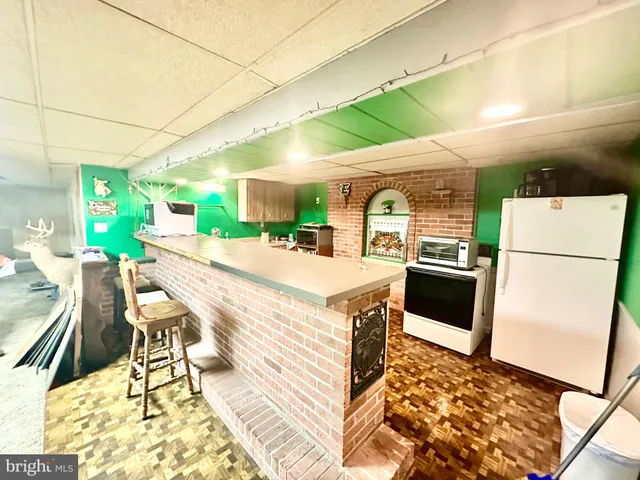 a kitchen with stainless steel appliances granite countertop a refrigerator a stove a sink a dining table and chairs with wooden floor