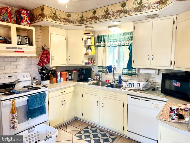 a kitchen with granite countertop a stove a sink and dishwasher wooden cabinets with granite countertops