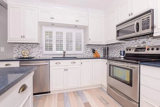 a kitchen with granite countertop white cabinets and white appliances