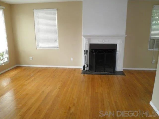 an empty room with windows and fireplace