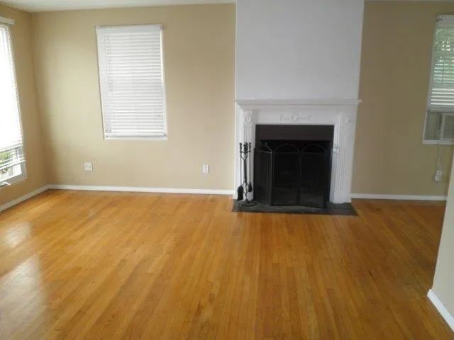 a view of an empty room with wooden floor and a fireplace