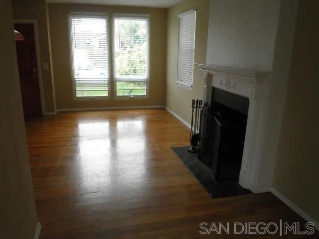 an empty room with windows and fireplace