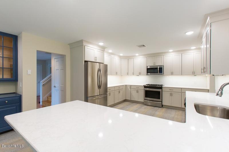 755 Tyringham Road Lee, MA 01238 - Photo 13 of 32 a large white kitchen with kitchen island a sink a stove a refrigerator and white cabinets