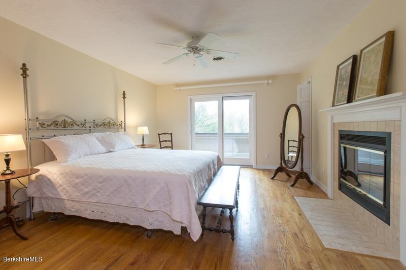 755 Tyringham Road Lee, MA 01238 - Photo 18 of 32 a bedroom with a bed a fireplace and a large window