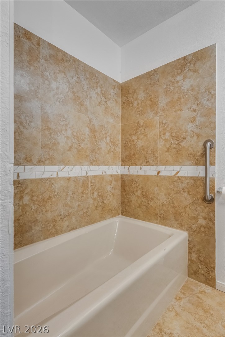 524 Swallow Cove Boulder City, NV 89005 - Photo 32 of 58 Step into a well-appointed bath with textured tile walls and a pristine tub.
