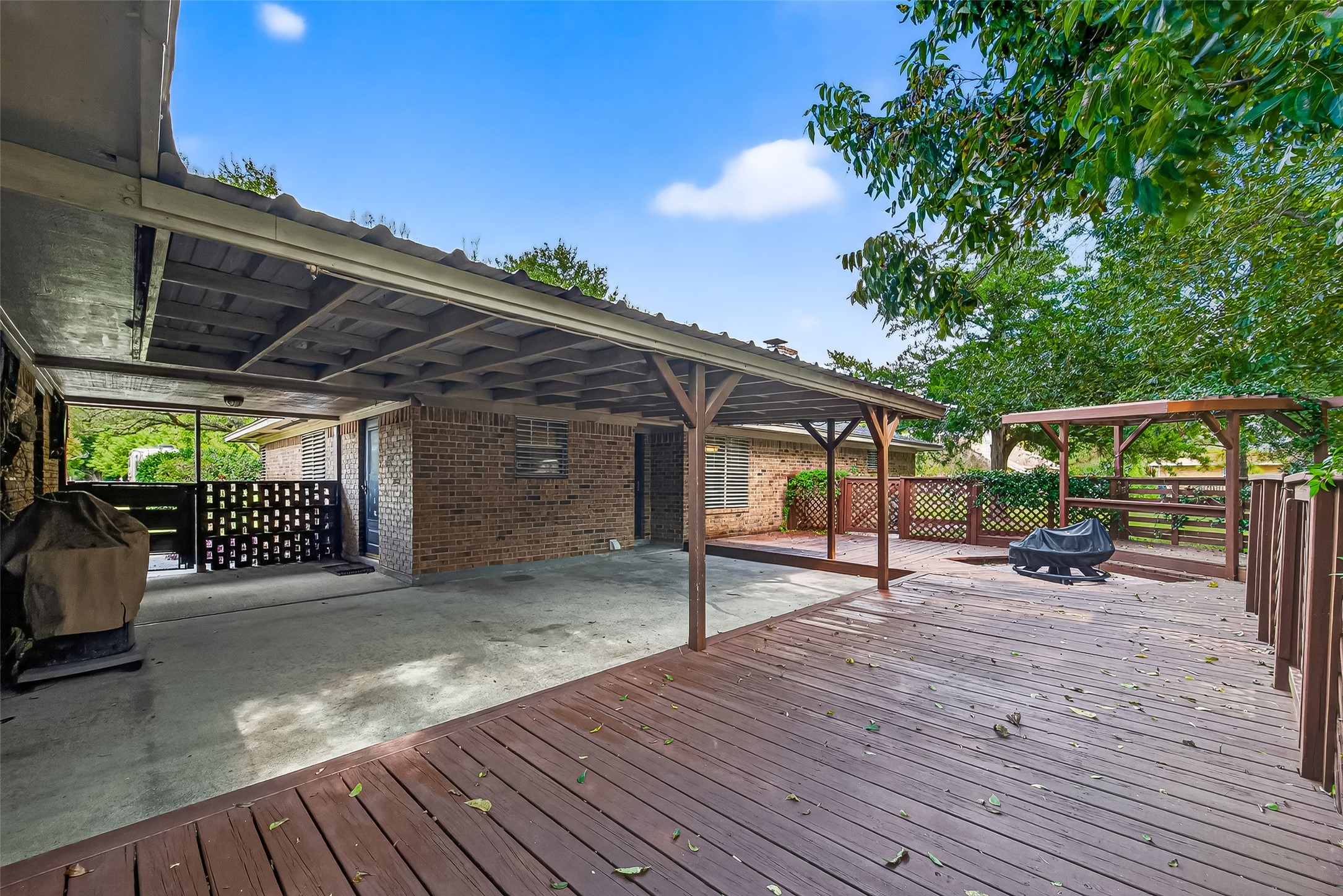 12021 7th 1/2 Street Santa Fe, TX 77510 - Photo 11 of 49 Spacious backyard with a large wooden deck and covered patio area. Ideal for outdoor entertaining and relaxing, surrounded by mature trees for added privacy.