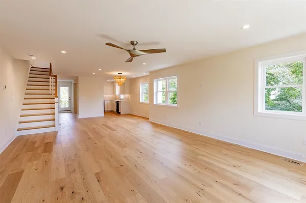 an empty room with wooden floor fan and windows