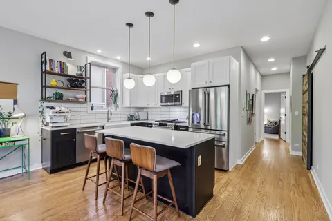 a kitchen with stainless steel appliances a stove a sink a refrigerator a center island and a stove