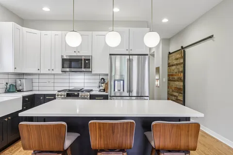 a kitchen with stainless steel appliances granite countertop a sink a stove a refrigerator cabinets and living room view