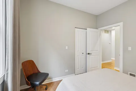 a bedroom with a chair and a window