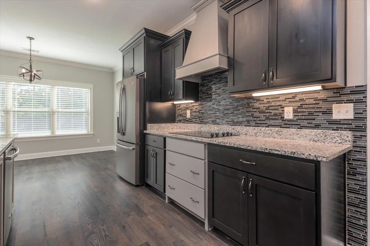 3328 Straw Bridge Road Olive Branch, MS 38654 - Photo 13 of 28 Sleek kitchen featuring dark wood-finish cabinetry, stainless steel appliances, speckled countertops, and a modern tile backsplash