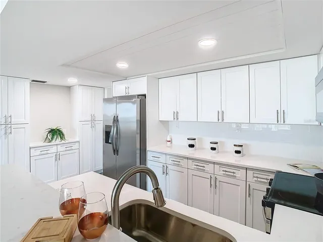 a kitchen with stainless steel appliances a sink a stove a refrigerator cabinets and a dining table