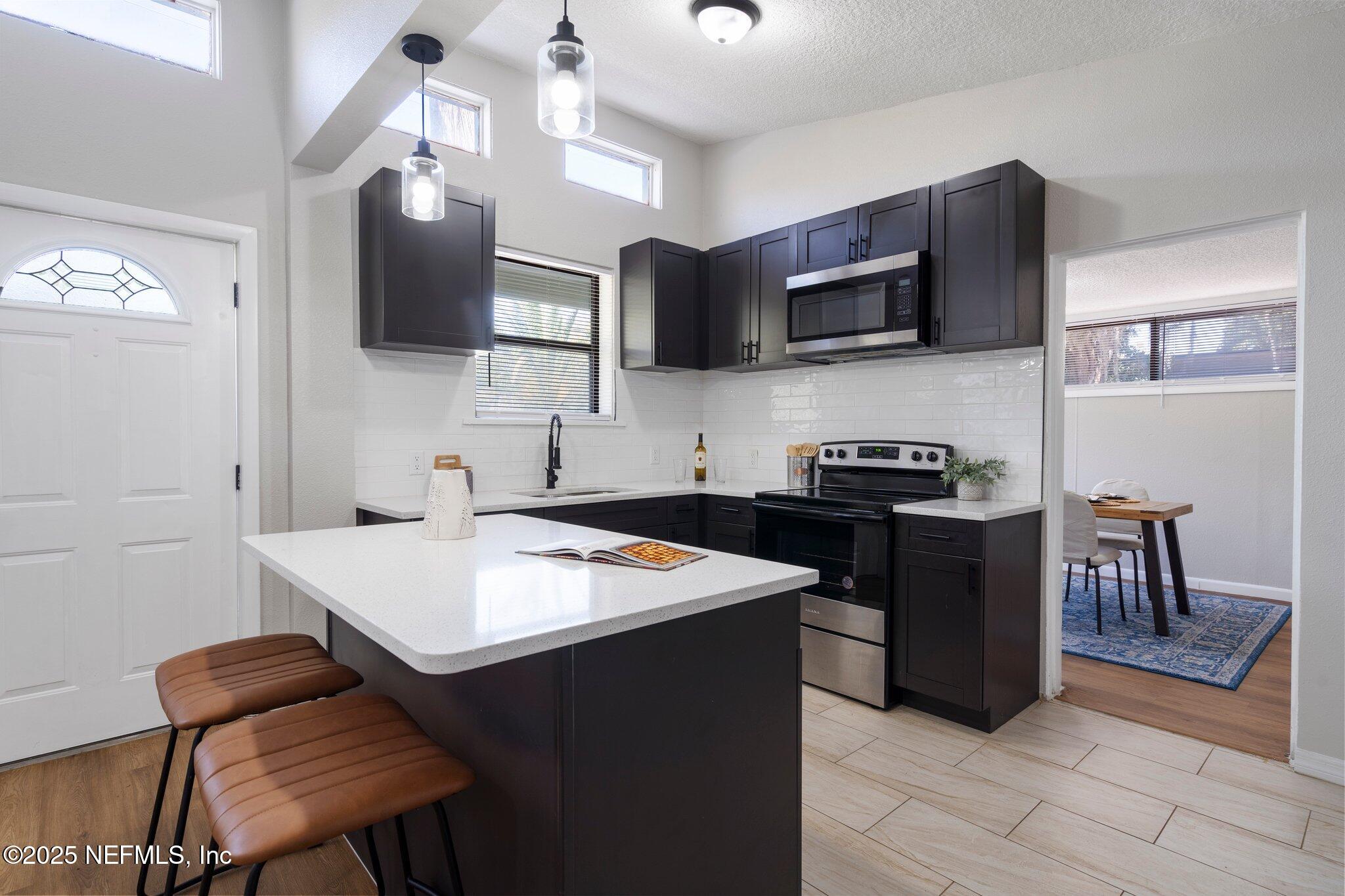 2838 Rainbow Road Jacksonville, FL 32217 - Photo 9 of 35 a kitchen with stainless steel appliances granite countertop a sink dishwasher a stove top oven a dining table and chairs with wooden floor