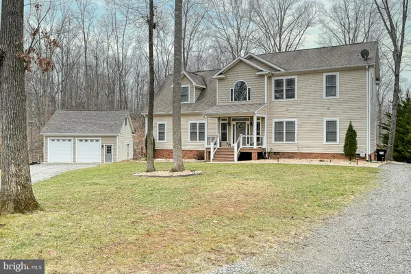 a view of living room kitchen with stainless steel appliances wooden floor and table chairs