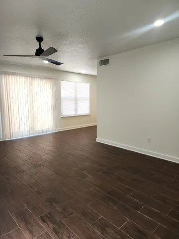 an empty room with wooden floor fan and windows