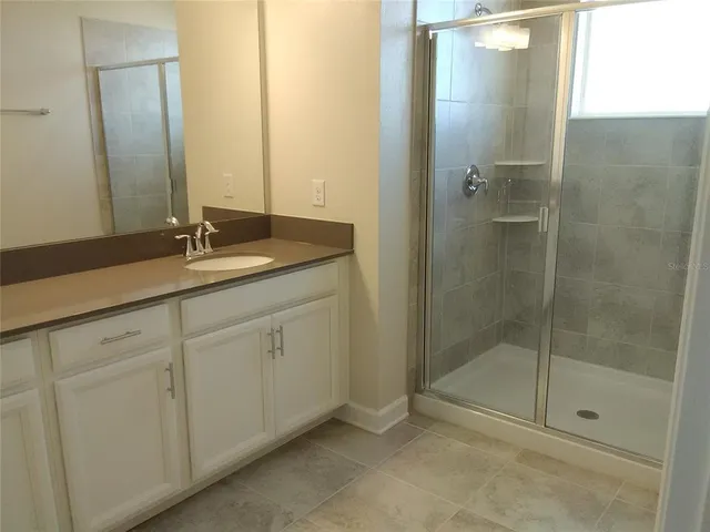 a bathroom with a shower sink and mirror