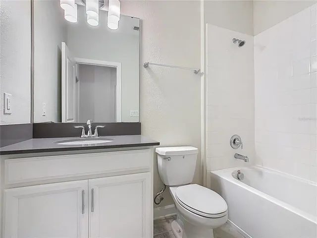 a bathroom with a granite countertop toilet a sink and a bathtub