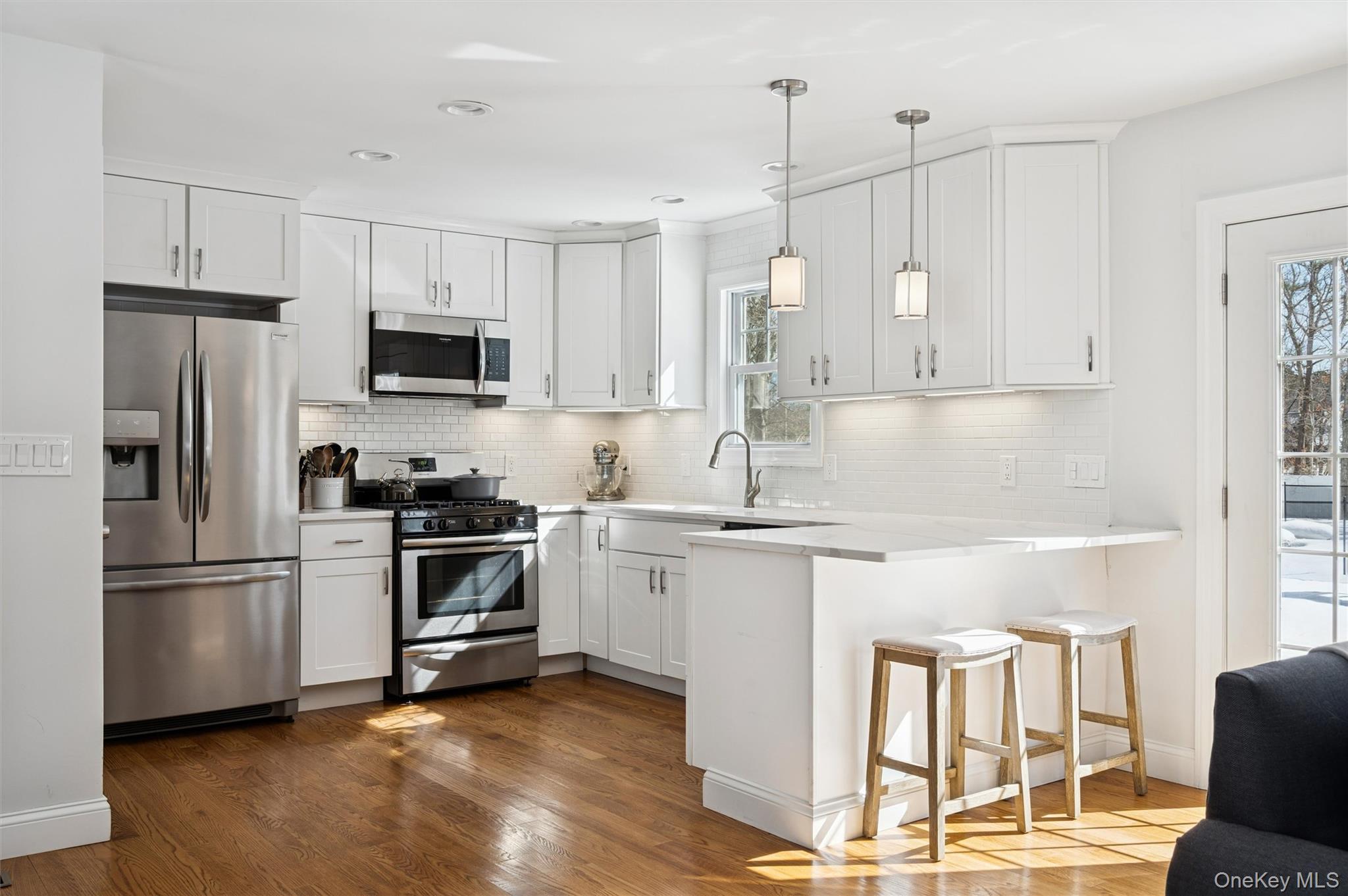 4 Stuart Court Hampton Bays, NY 11946 - Photo 3 of 20 a kitchen with kitchen island white cabinets and stainless steel appliances