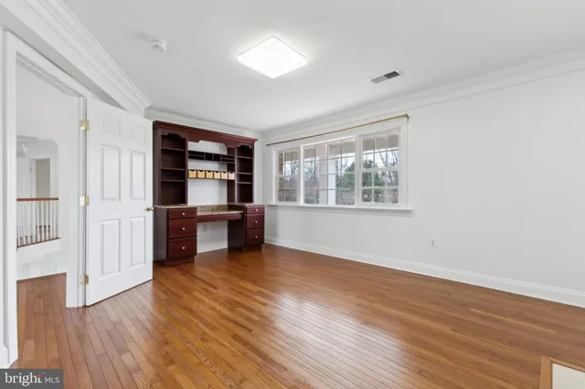 a view of an empty room with window and wooden floor