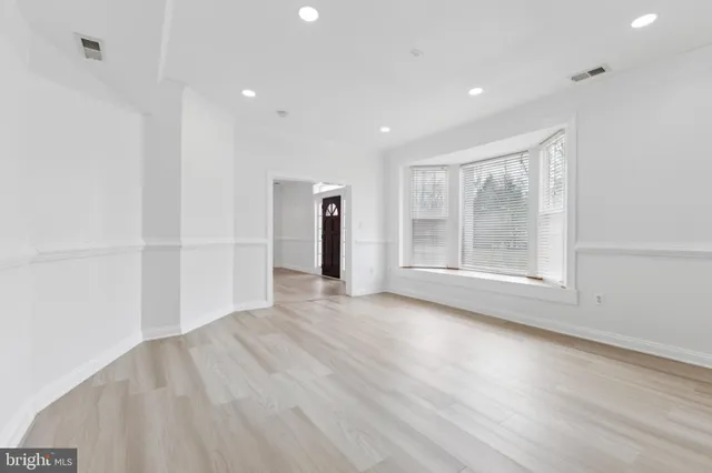 a view of an empty room with wooden floor and windows