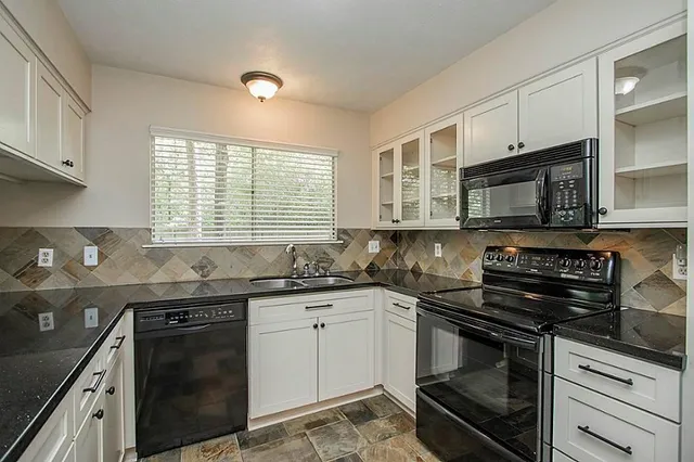 a kitchen with stainless steel appliances kitchen island granite countertop a table chairs sink and cabinets