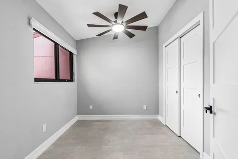 an empty room with windows and fan