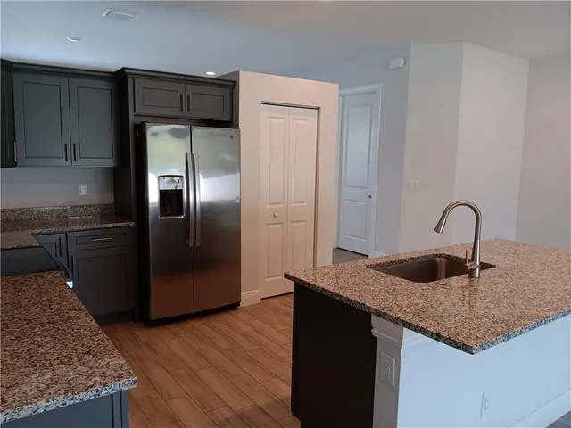 a kitchen with granite countertop a refrigerator and a sink