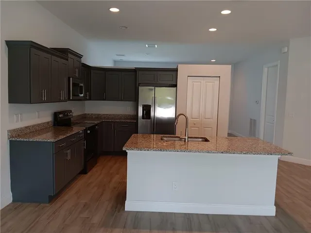 a large kitchen with granite countertop a sink a stove and refrigerator