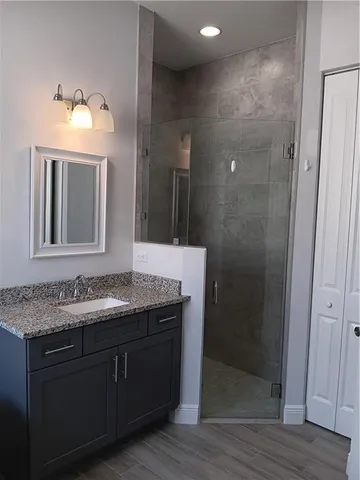 a bathroom with a granite countertop sink a mirror and shower
