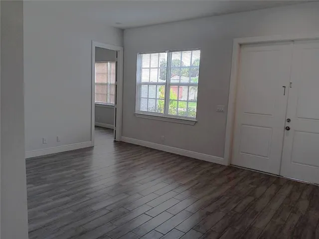 an empty room with wooden floor and windows