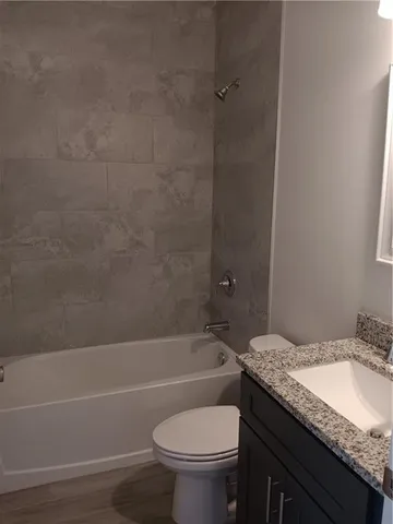 a bathroom with a granite countertop toilet sink and bathtub