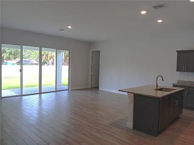 a kitchen with stainless steel appliances granite countertop a sink a counter space and wooden floor