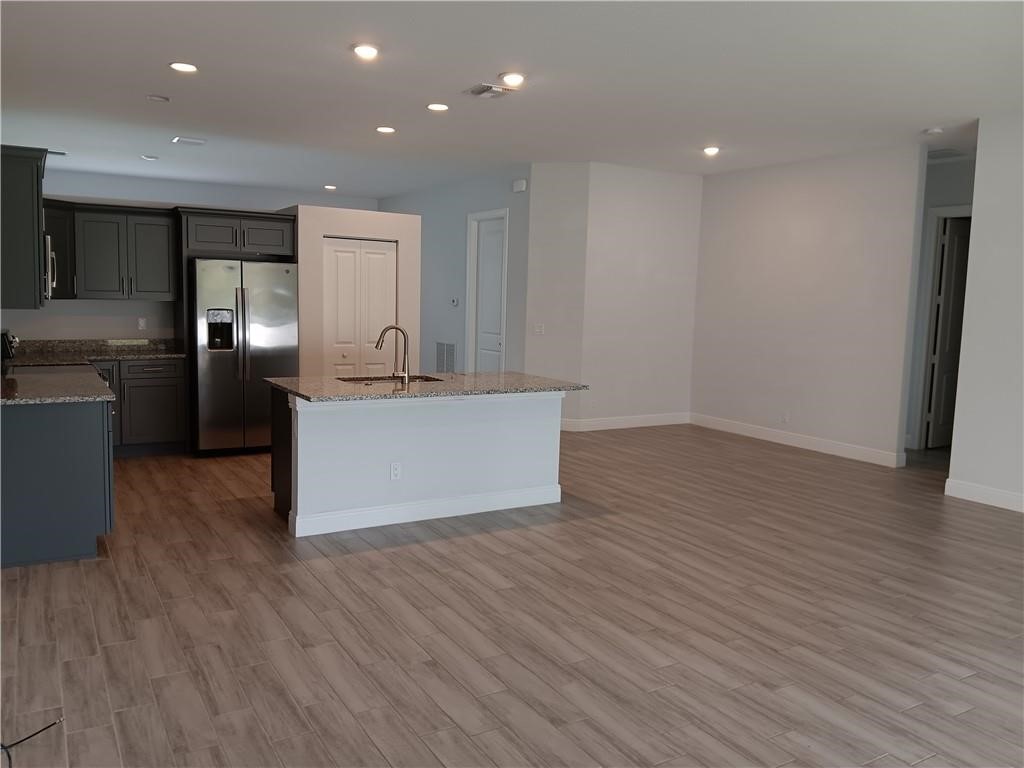 2121 Bridgehampton Terrace Vero Beach, FL 32966 - Photo 7 of 33 an empty room with wooden floor and kitchen view