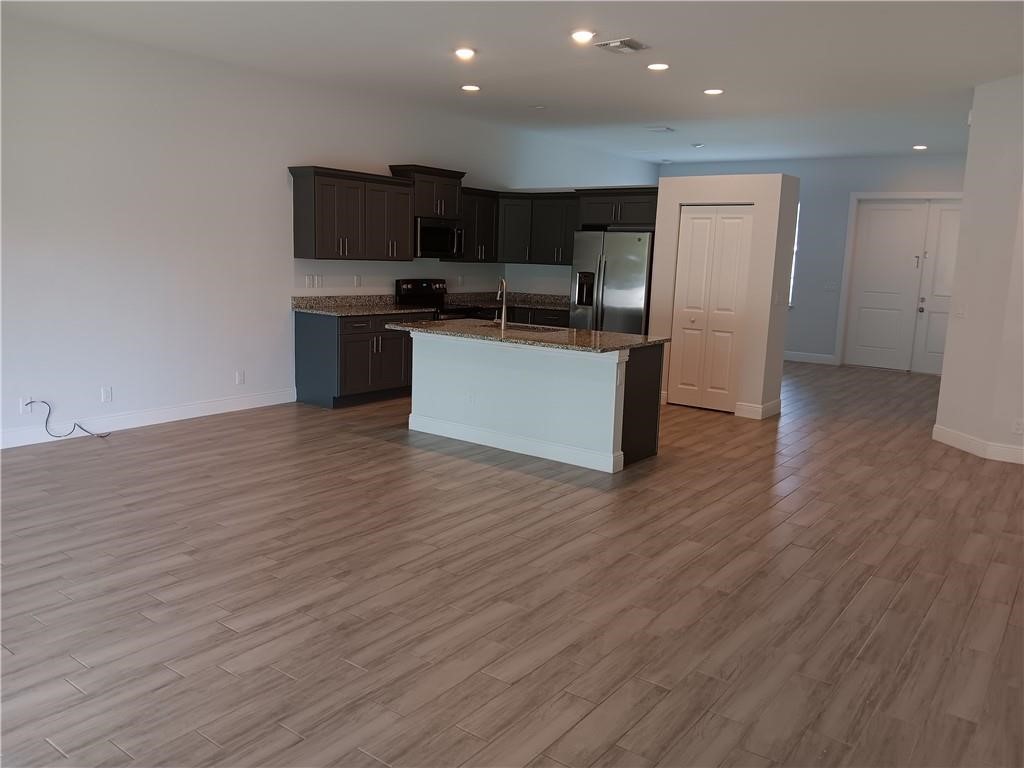 2121 Bridgehampton Terrace Vero Beach, FL 32966 - Photo 9 of 33 a kitchen with stainless steel appliances kitchen island wooden cabinets and granite counter tops