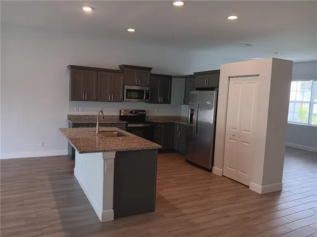 a kitchen with kitchen island stainless steel appliances a sink stove and refrigerator