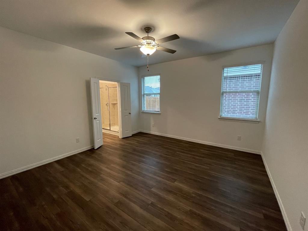 3700 Milkweed Road McKinney, TX 75071 - Photo 10 of 18 Spacious room featuring wood-finish flooring, two windows with blinds, a ceiling fan with integrated lighting, and a double-door entry to a bathroom with a glass-enclosed shower