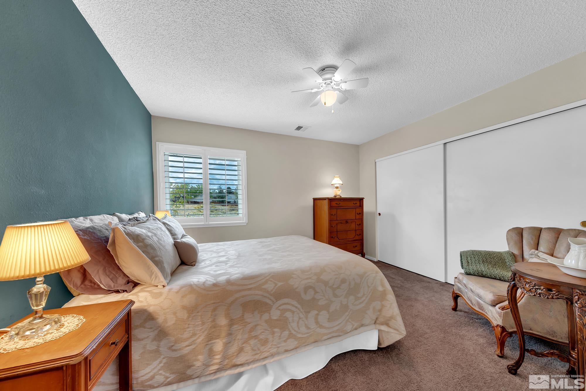 5861 Bankside Way Reno, NV 89523 - Photo 23 of 39 a bedroom with a bed a couch and a lamp on dresser
