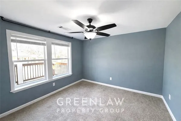 an empty room with windows and ceiling fan