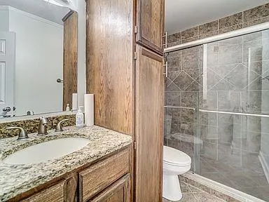 a bathroom with a granite countertop sink a toilet and shower