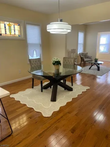 a living room with table chairs and a wooden floor