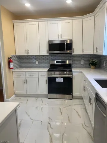 a kitchen with white cabinets and appliances