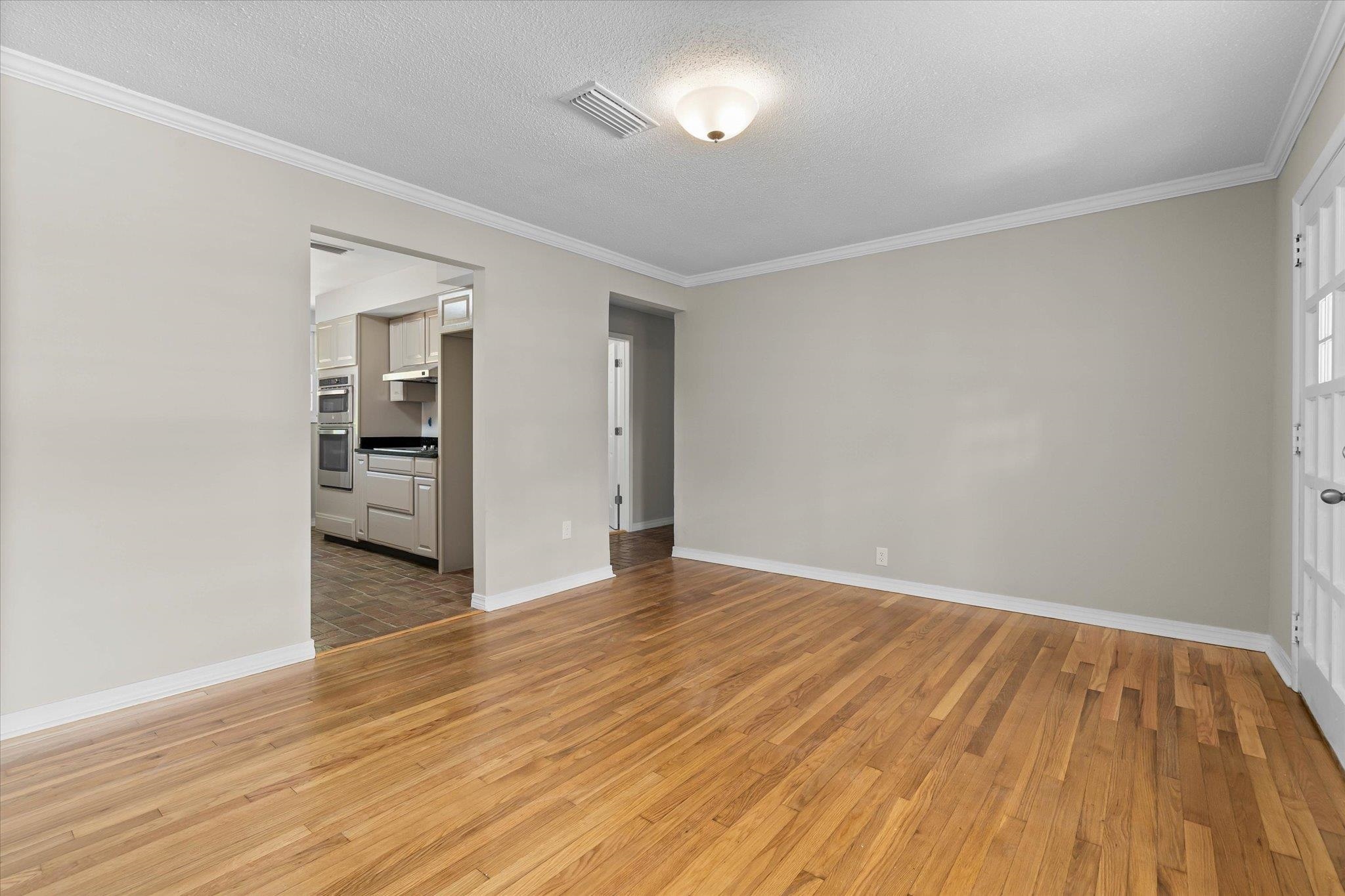 4700 Bit And Spur Road Mobile, AL 36608 - Photo 4 of 21 Empty room featuring light wood-type flooring, visible vents, a textured ceiling, and crown molding