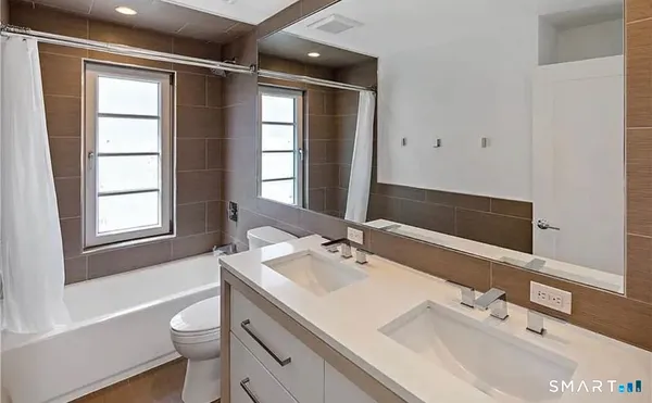 a bathroom with a sink double vanity granite tub and a toilet